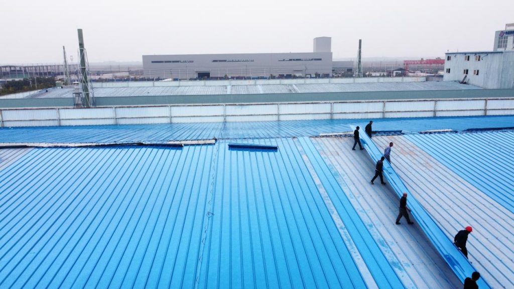 1 workers installing blue metal roof in industrial area