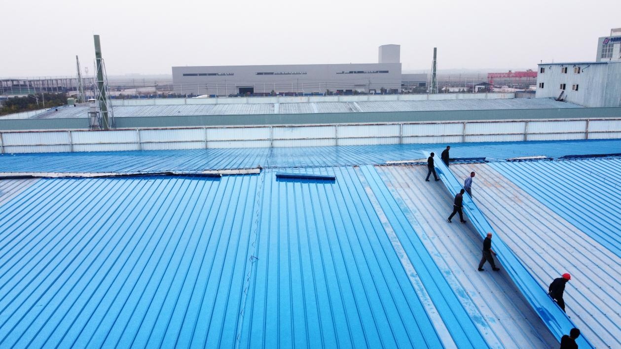 1 workers installing blue metal roof in industrial area